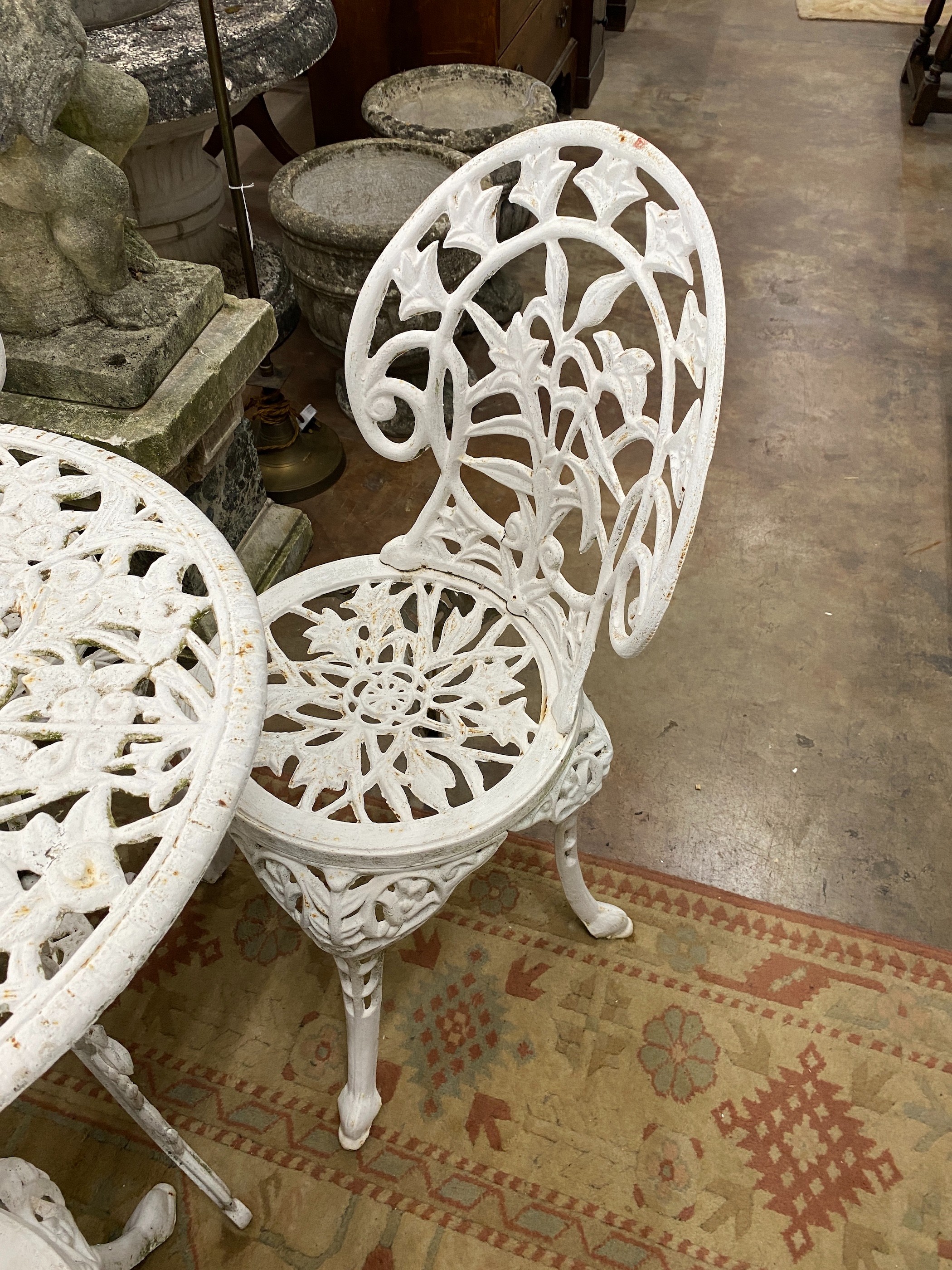 A Victorian style painted cast iron circular garden table, diameter 62cm, height 67cm together with four matching chairs